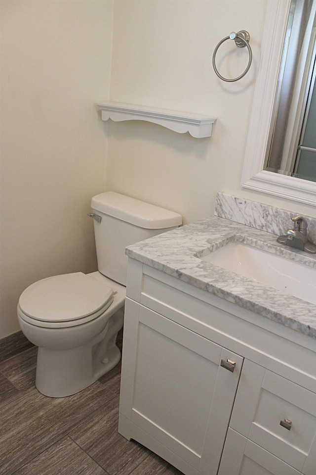 half bathroom with vanity, toilet, and wood finished floors