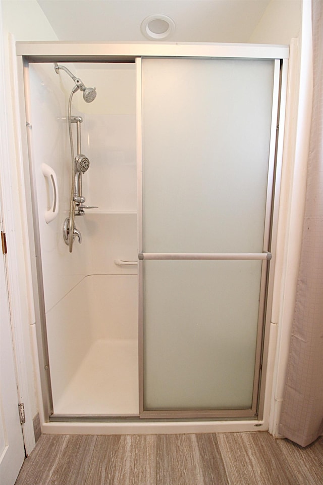 full bath featuring wood finished floors and a stall shower