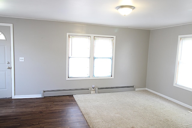 interior space featuring a baseboard heating unit, plenty of natural light, baseboard heating, and dark wood-type flooring