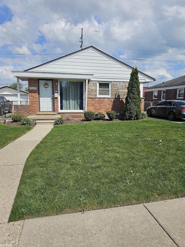 bungalow-style house with brick siding and a front lawn