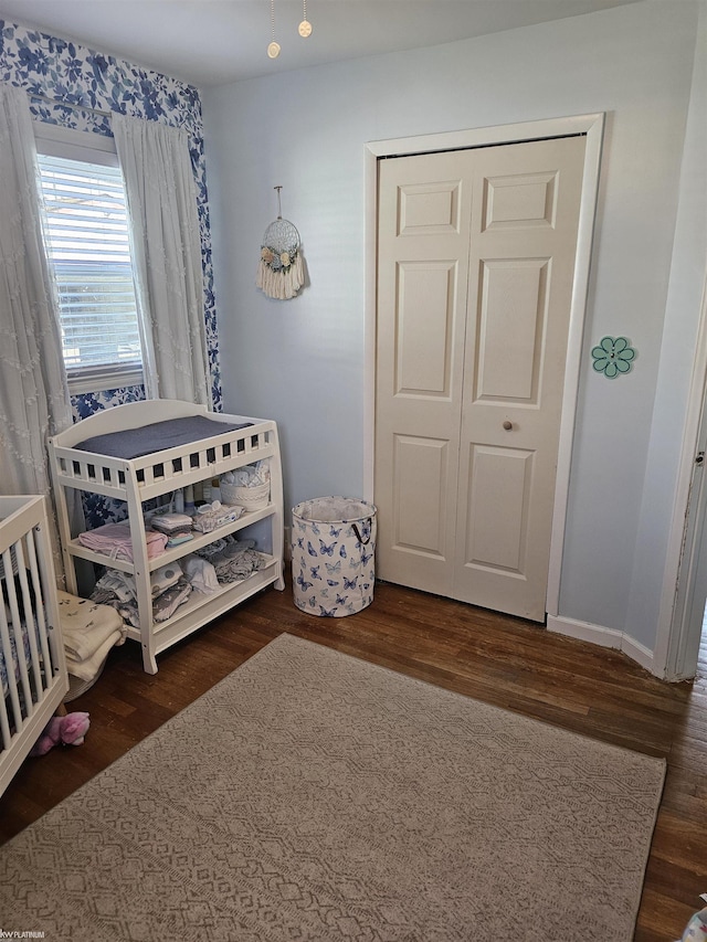 bedroom featuring baseboards, wood finished floors, and a closet
