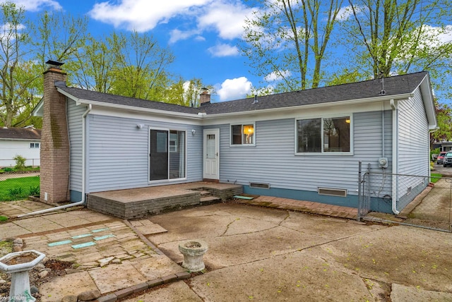back of house featuring roof with shingles, fence, a chimney, and a patio area