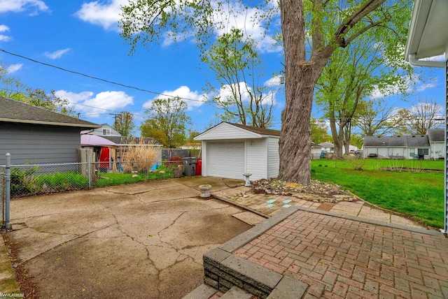 view of patio featuring concrete driveway, fence, an outbuilding, and a detached garage
