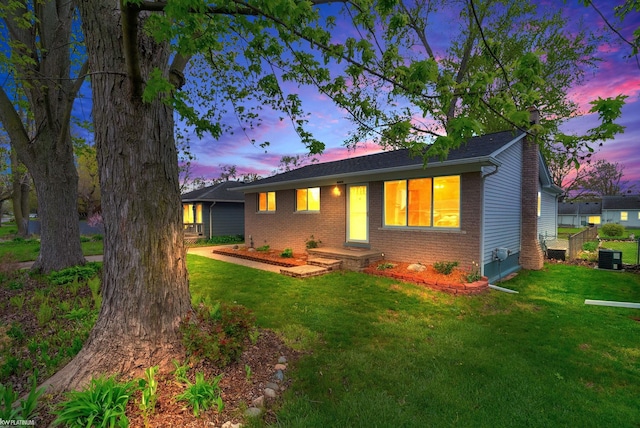 ranch-style home featuring brick siding, a lawn, and cooling unit