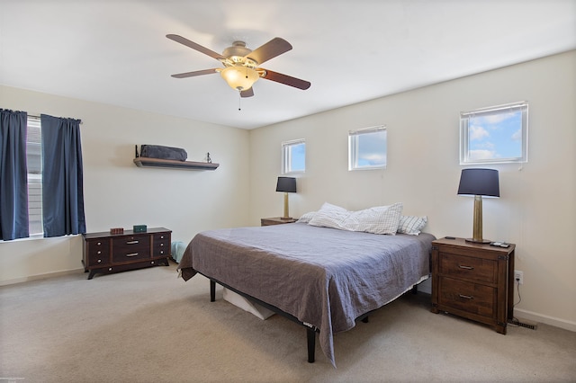 bedroom featuring light colored carpet, baseboards, and ceiling fan
