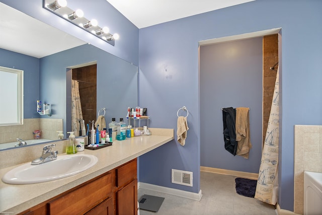 bathroom featuring baseboards, visible vents, a tub to relax in, and vanity
