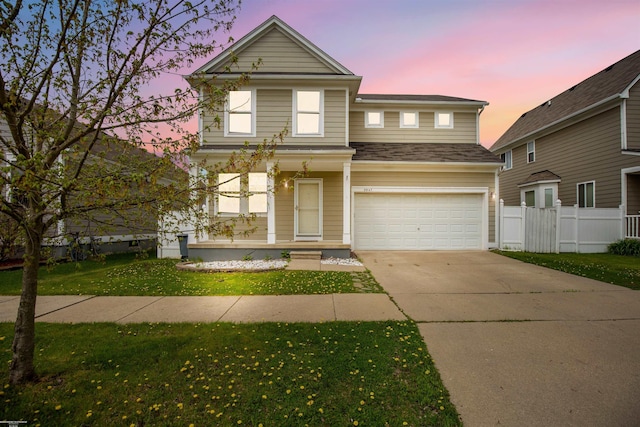 traditional home featuring fence, roof with shingles, an attached garage, concrete driveway, and a yard