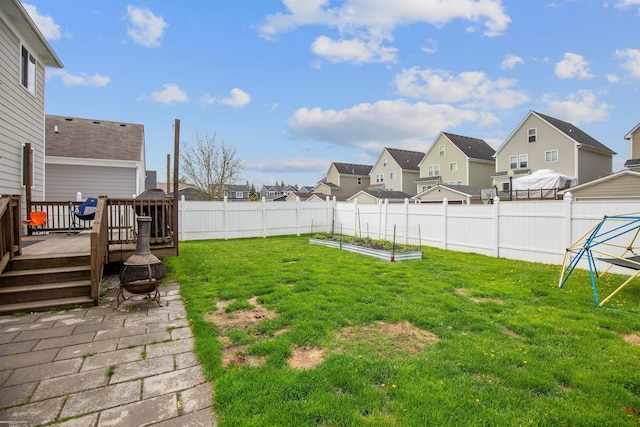 view of yard with a fenced backyard, a vegetable garden, a residential view, and a deck