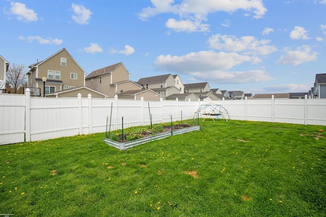 view of yard featuring a residential view, a fenced backyard, and a vegetable garden