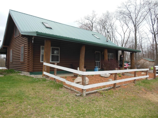 view of side of home with a lawn, covered porch, log exterior, and metal roof