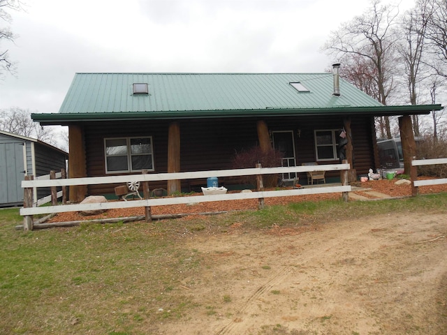 view of front of home with metal roof, covered porch, and log siding
