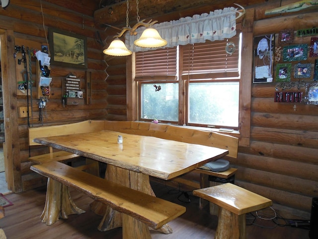 dining space featuring breakfast area, log walls, and wood finished floors
