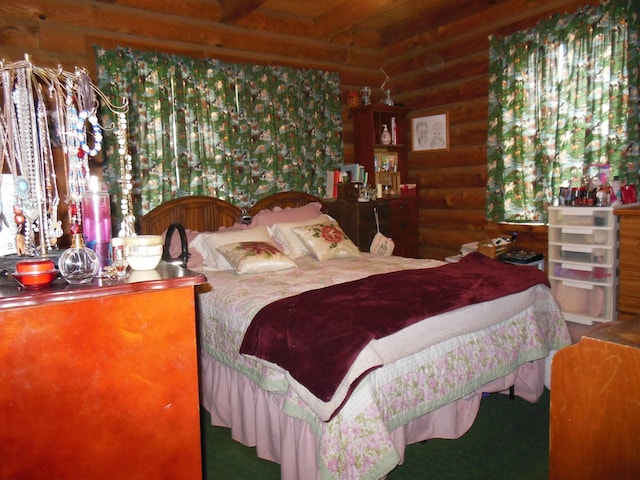 bedroom with beamed ceiling and log walls