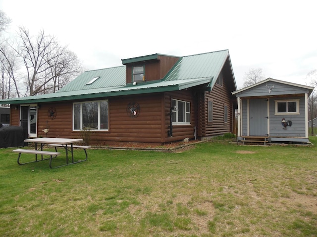 rear view of house with a lawn, an outbuilding, log siding, and metal roof