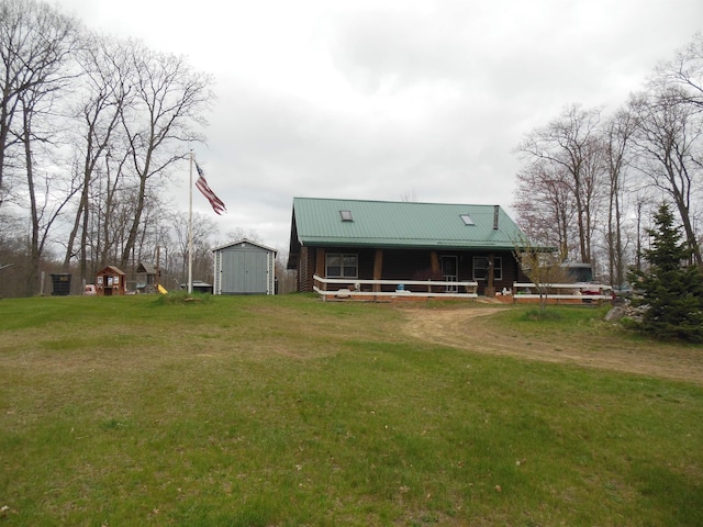 rear view of house with a lawn, an outbuilding, metal roof, and a shed