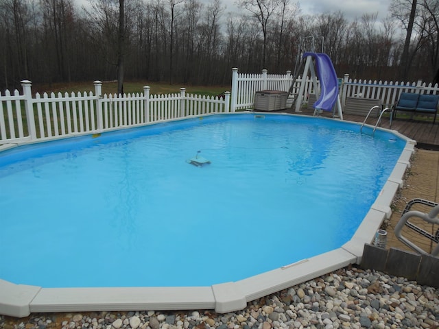 view of swimming pool featuring fence, a water slide, and a fenced in pool