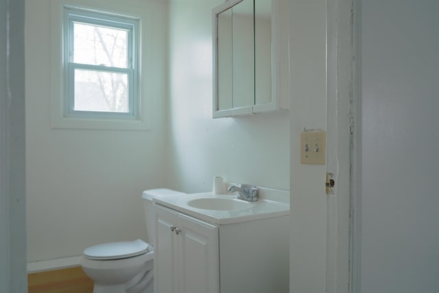half bath with vanity, baseboards, and toilet