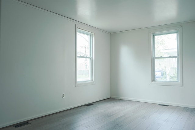 spare room featuring plenty of natural light, wood finished floors, and visible vents