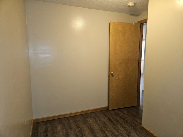 spare room with baseboards, a textured ceiling, and dark wood-style floors