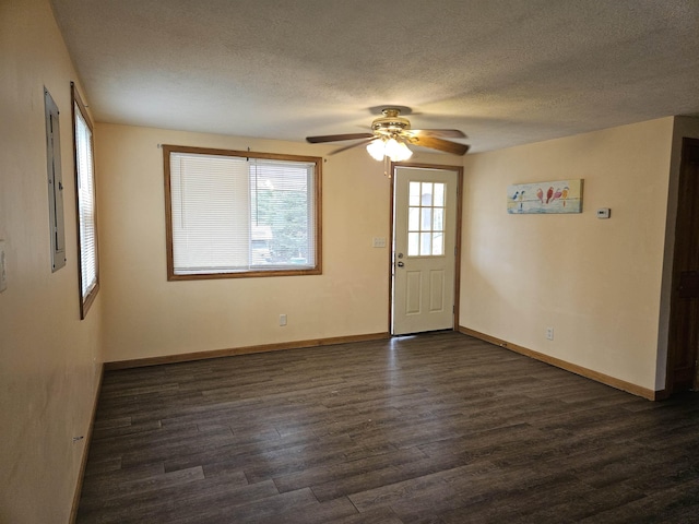 unfurnished room with a ceiling fan, a textured ceiling, baseboards, and dark wood-type flooring