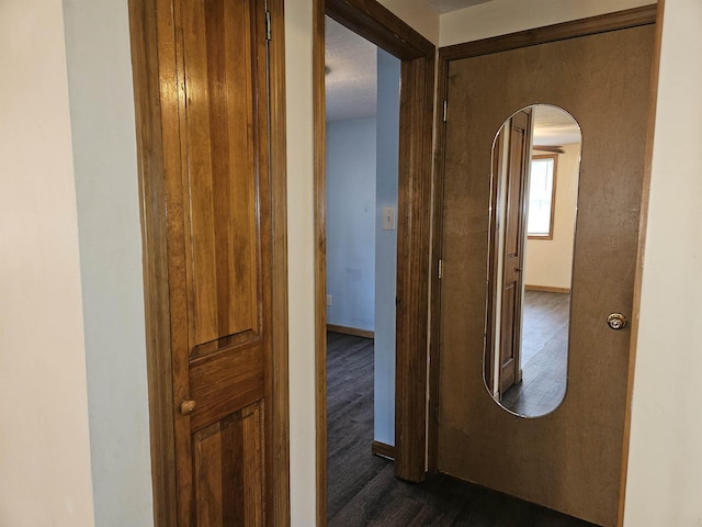 corridor with arched walkways, baseboards, and dark wood finished floors