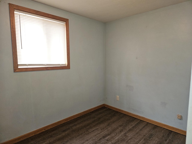 empty room with baseboards and dark wood finished floors