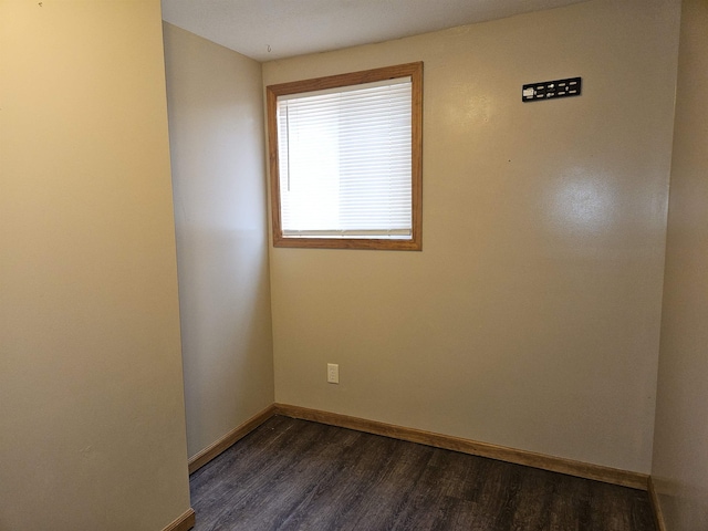 empty room with baseboards and dark wood-type flooring