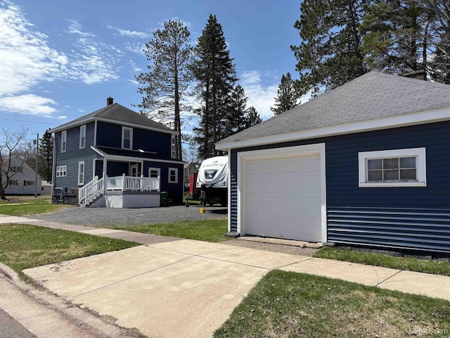 exterior space with a shingled roof, a garage, a front yard, an outdoor structure, and driveway