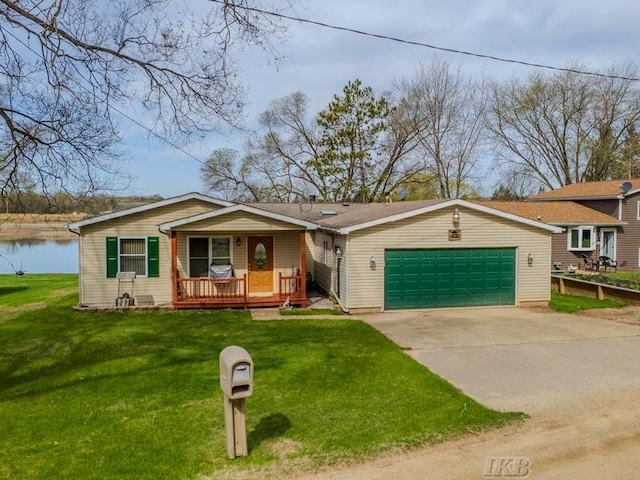 view of front of home with covered porch, driveway, a front yard, a water view, and an attached garage