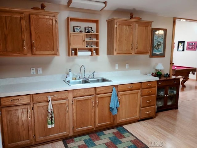 kitchen with open shelves, a sink, light wood finished floors, light countertops, and pool table