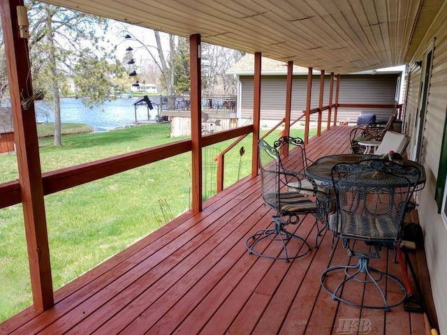 wooden deck with outdoor dining area, a water view, and a yard
