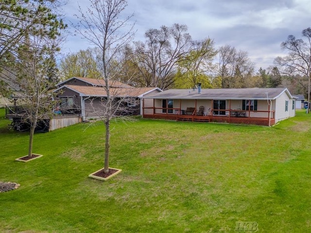 rear view of house featuring a wooden deck and a yard