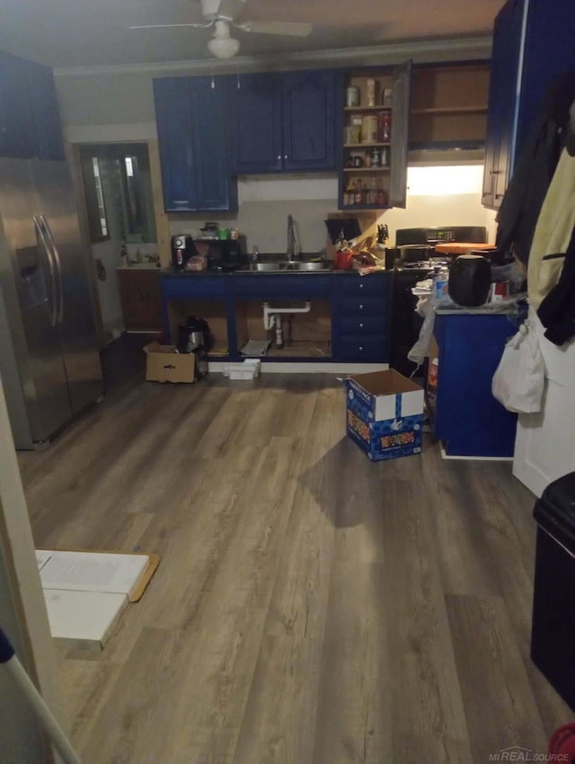 kitchen with a ceiling fan, a sink, wood finished floors, stainless steel fridge, and blue cabinets