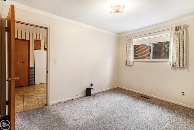 carpeted spare room with baseboards, ornamental molding, and visible vents