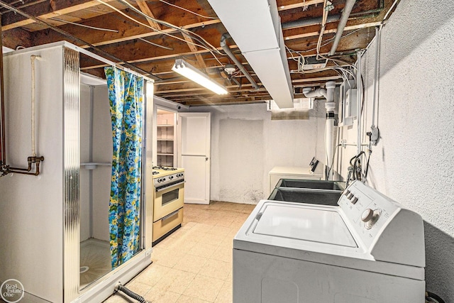 clothes washing area with a textured wall, laundry area, washing machine and dryer, and light floors