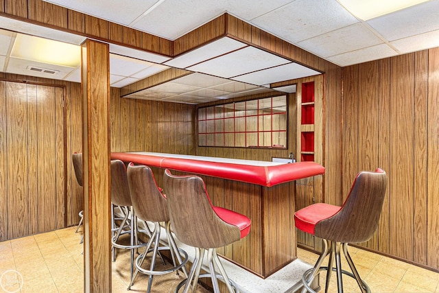 bar featuring visible vents, wood walls, tile patterned floors, and a dry bar