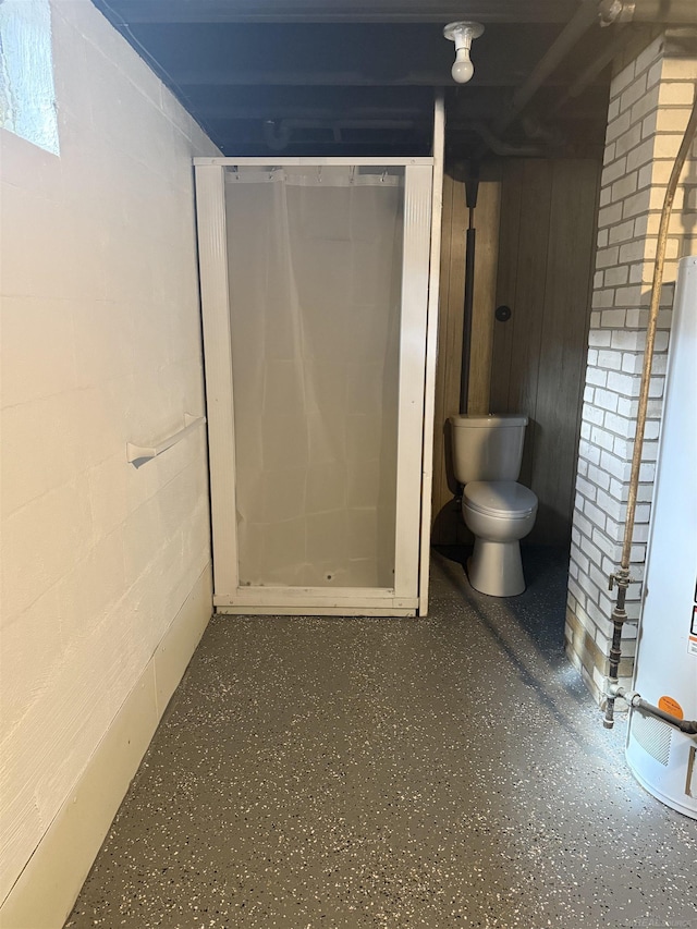 bathroom featuring concrete block wall, walk in shower, and toilet