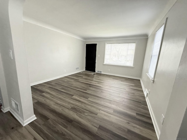spare room featuring visible vents, dark wood finished floors, and a wealth of natural light