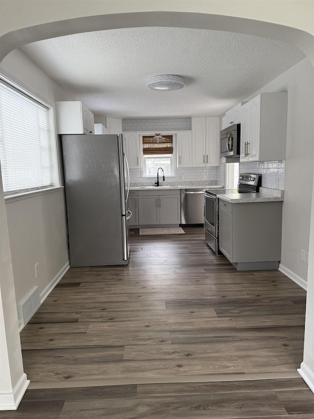 kitchen with a sink, light countertops, stainless steel appliances, decorative backsplash, and visible vents
