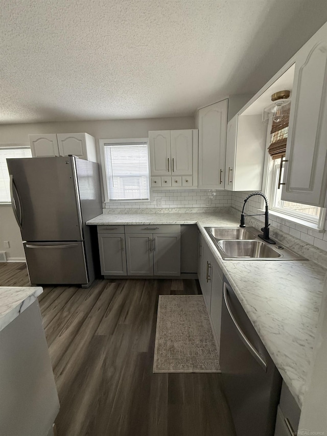 kitchen featuring a sink, appliances with stainless steel finishes, dark wood-style flooring, and a textured ceiling