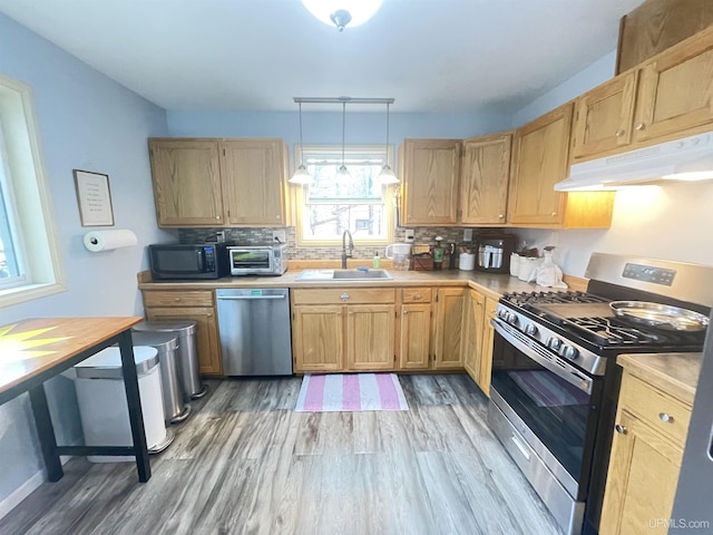 131 Midway Dr, Negaunee, MI 49866 - kitchen featuring stainless steel appliances, under cabinet range hood, a sink, light wood-style flooring, and decorative backsplash