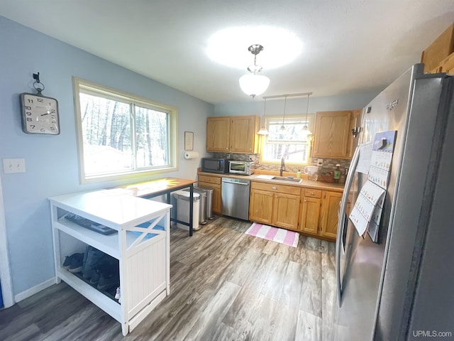 131 Midway Dr, Negaunee, MI 49866 - kitchen with appliances with stainless steel finishes, light wood finished floors, a sink, light countertops, and backsplash