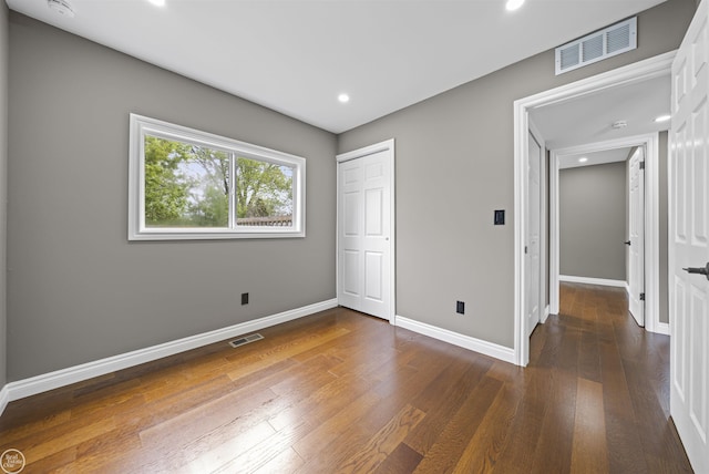 unfurnished bedroom with baseboards, wood-type flooring, recessed lighting, and visible vents