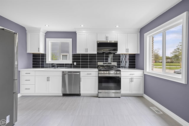 kitchen featuring light countertops, tasteful backsplash, stainless steel appliances, and visible vents
