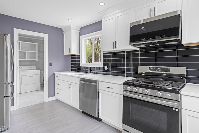 kitchen featuring light countertops, appliances with stainless steel finishes, tasteful backsplash, and washer / clothes dryer