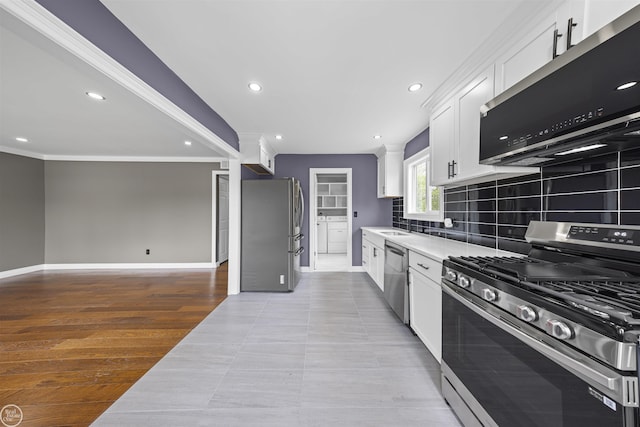 kitchen featuring backsplash, a sink, light countertops, white cabinets, and stainless steel appliances
