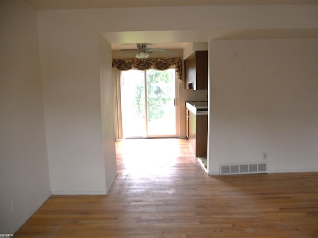 hall featuring baseboards, light wood-style flooring, and visible vents
