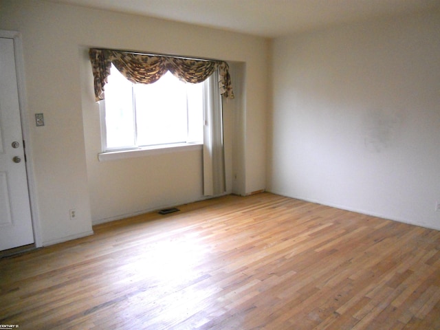 unfurnished room featuring visible vents and light wood-style flooring