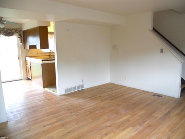 unfurnished living room featuring visible vents, a ceiling fan, baseboards, and light wood-type flooring