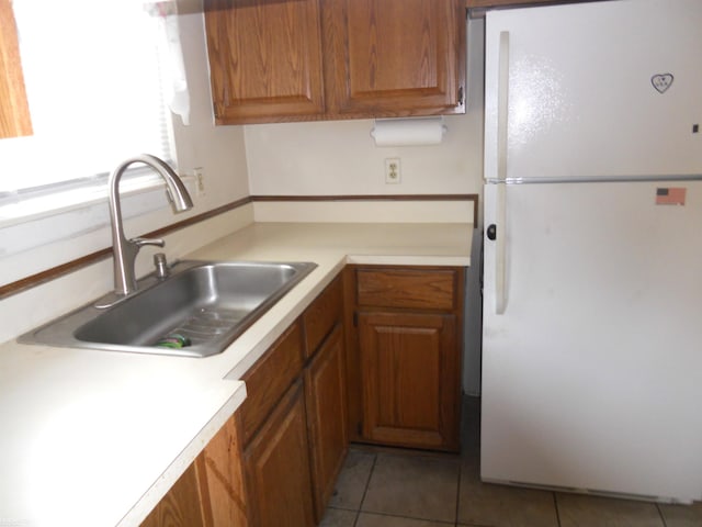 kitchen featuring freestanding refrigerator, a sink, tile patterned floors, and light countertops
